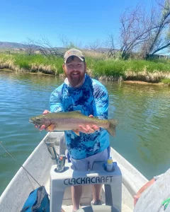 Fly fishing guide helping client land a Rainbow trout in Wyoming