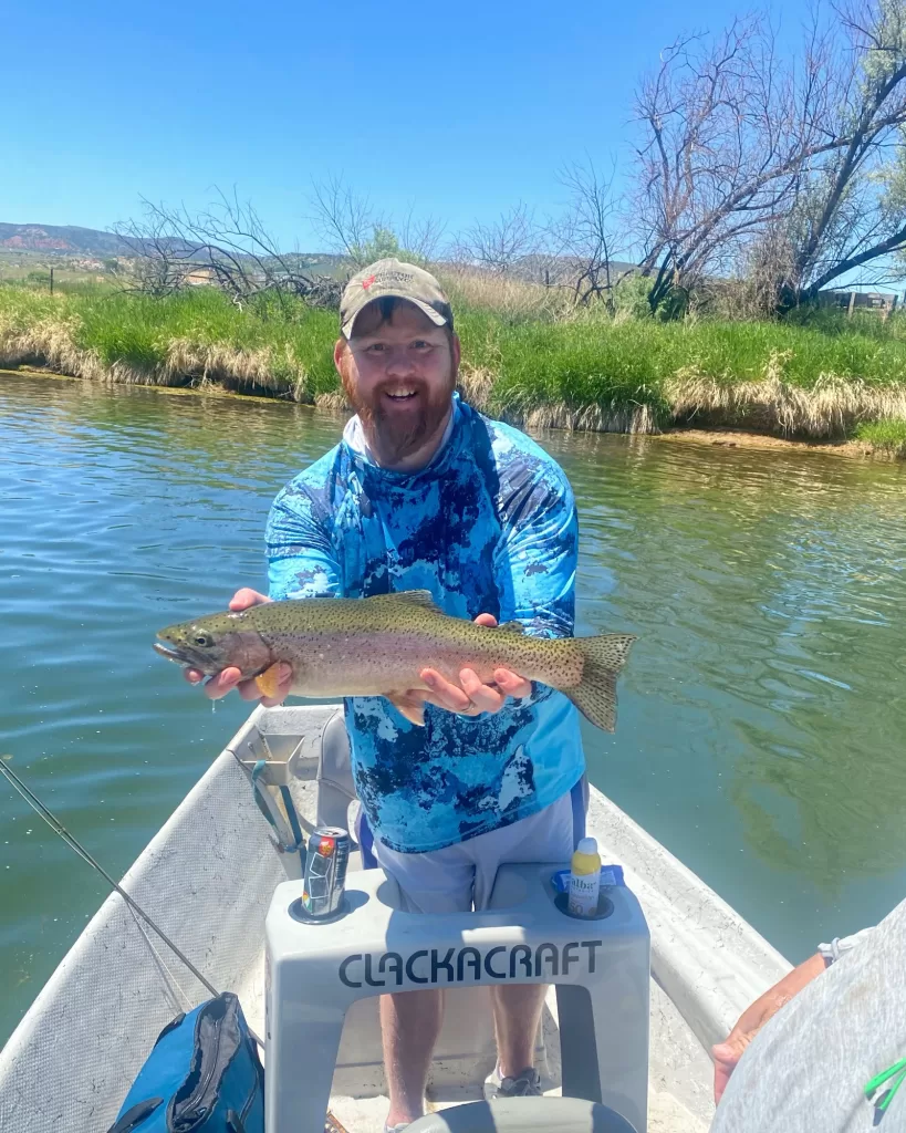 Fly fishing guide helping client land a Rainbow trout in Wyoming